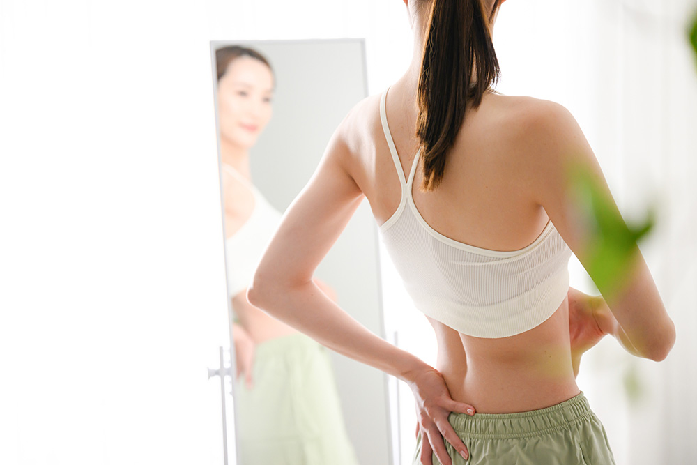 女性鏡の前でおなかさわる