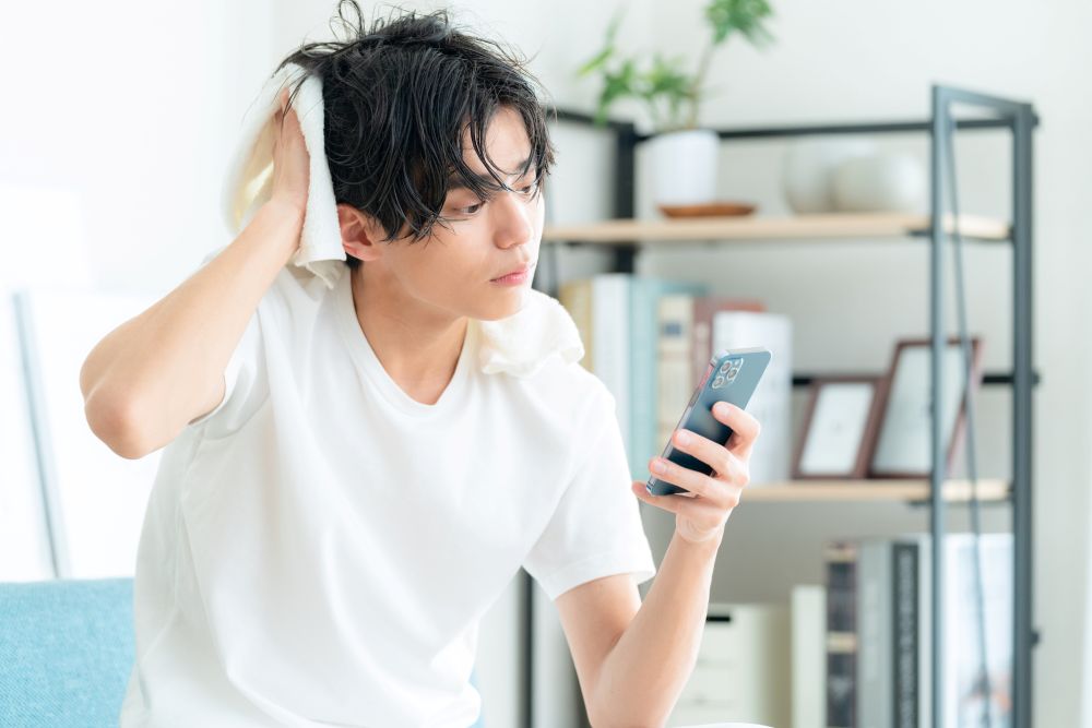 スマホを見ながら髪を拭く男性