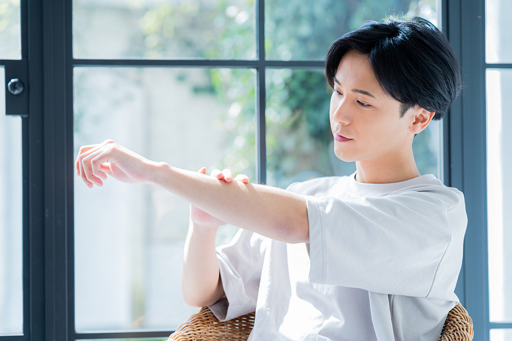 腕をなでる男性